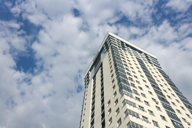 Vista del edificio de gran altura desde abajo contra un cielo azul con nubes blancas durante el día