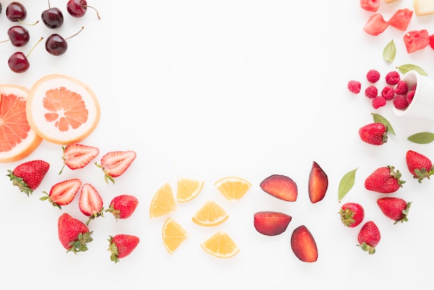 Una vista elevada de las cerezas; pomelo; fresas; limón; ciruelas fresas; Sandía y frambuesas sobre fondo blanco