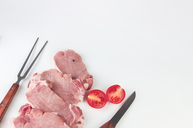 Vista elevada de filetes de carne cruda para asar sobre fondo blanco con ingredientes para cocinar