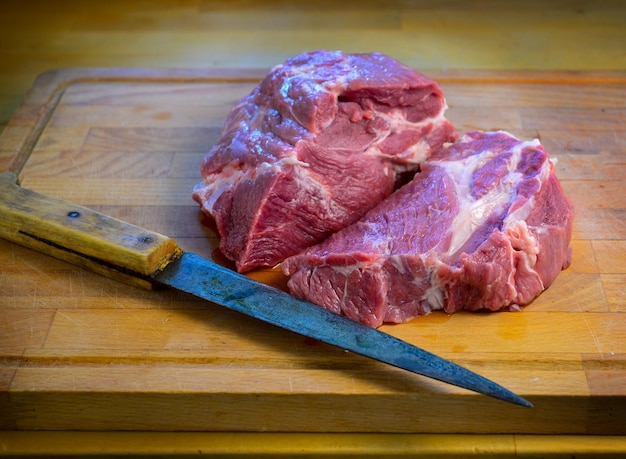 Vista em alto ângulo da carne na tábua de cortar ao lado da faca