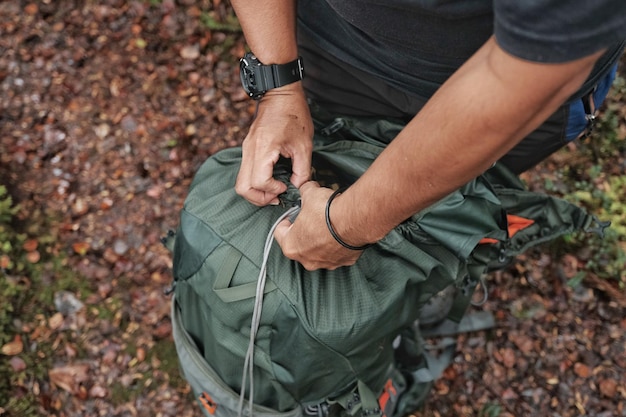 Vista em alto ângulo de um homem abrindo uma mochila no campo