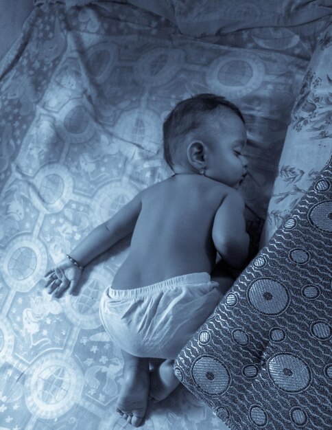 Foto vista em alto ângulo de um menino sem camisa dormindo no berço em casa