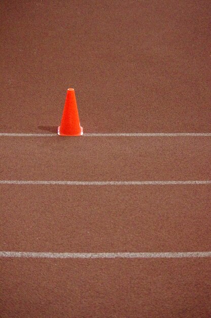 Foto vista em alto ângulo do cone de tráfego vermelho na pista de corrida