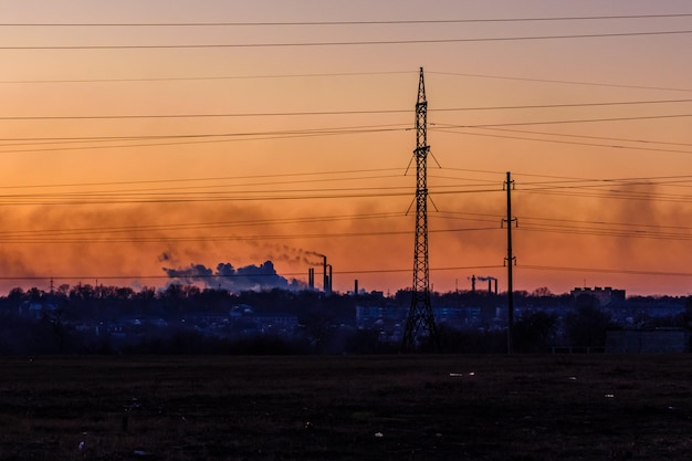 Vista em cachimbos de fumaça da fábrica ao pôr do sol
