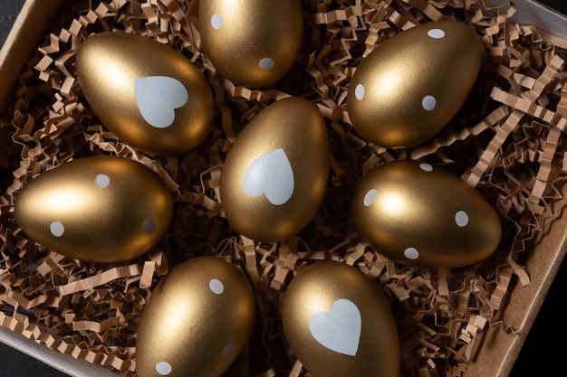 Foto vista em close-up de ovos de ouro em caixa de papel em uma mesa escura