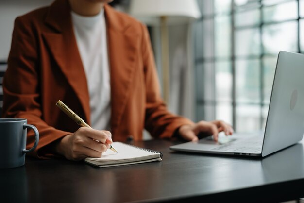 Vista em close-up de um jovem empresário profissional escrevendo seus conceitos de idéia em um caderno enquanto trabalha em seu projeto