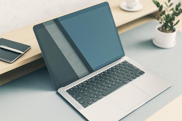 Vista em perspectiva de cima no monitor de laptop moderno escuro em branco com reflexo abstrato na mesa cinza claro com planta verde e notebook na maquete de renderização 3D de prateleira de madeira