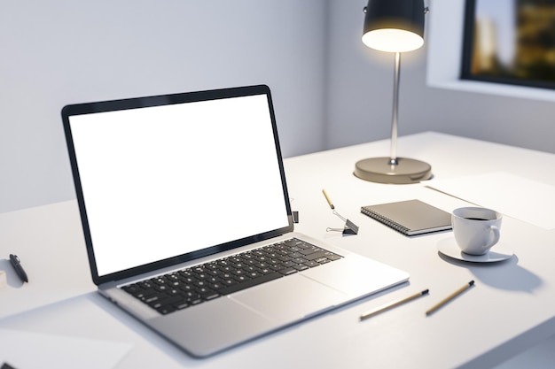 Vista em perspectiva na tela branca em branco do laptop moderno com espaço vazio na mesa de luz com ferramentas de escritório de lâmpada iluminada e xícara de café e vista da cidade noturna da janela renderização em 3D simulada