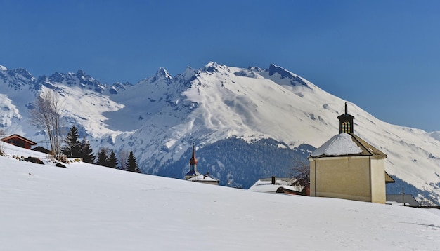 Vista em uma pequena capela na montanha alpina coberta de neve em savoie e sob o céu azul