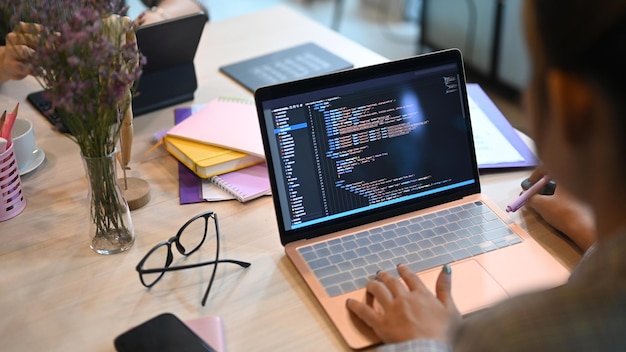Vista por encima del hombro de los desarrolladores de software programando en una computadora de escritorio en una oficina de inicio