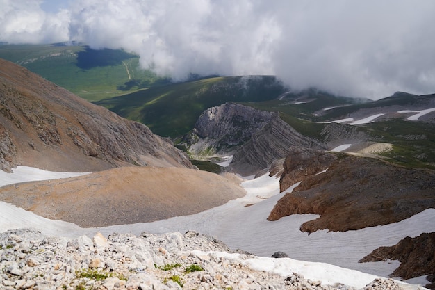 Foto vista épica del desfiladero de la montaña con glaciares cubiertos de nubes