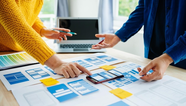 Vista del equipo de desarrolladores de la interfaz de usuario haciendo una lluvia de ideas sobre su proyecto con un teléfono inteligente portátil y una tableta digital Agencia de desarrollo digital creativaxA