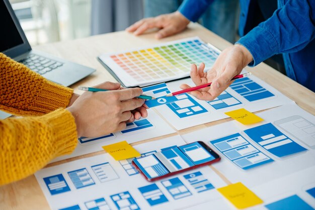 Vista del equipo de desarrolladores de la interfaz de usuario haciendo una lluvia de ideas sobre su proyecto con un teléfono inteligente portátil y una tableta digital Agencia de desarrollo digital creativaxA