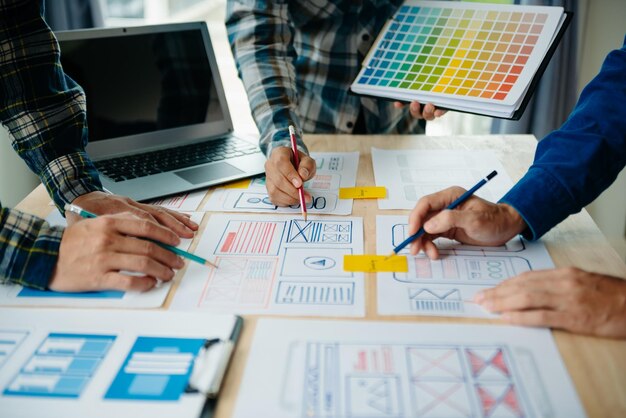 Vista del equipo de desarrolladores de la interfaz de usuario haciendo una lluvia de ideas sobre su proyecto con un teléfono inteligente portátil y una tableta digital Agencia de desarrollo digital creativaxA