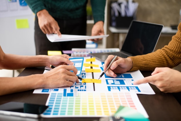 Vista del equipo de desarrolladores de la interfaz de usuario haciendo una lluvia de ideas sobre su proyecto con un teléfono inteligente portátil y una tableta digital Agencia de desarrollo digital creativaxA