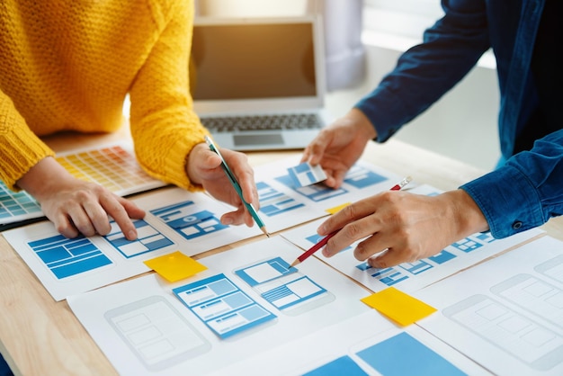 Vista del equipo de desarrolladores de la interfaz de usuario haciendo una lluvia de ideas sobre su proyecto con un teléfono inteligente portátil y una tableta digital Agencia de desarrollo digital creativaxA