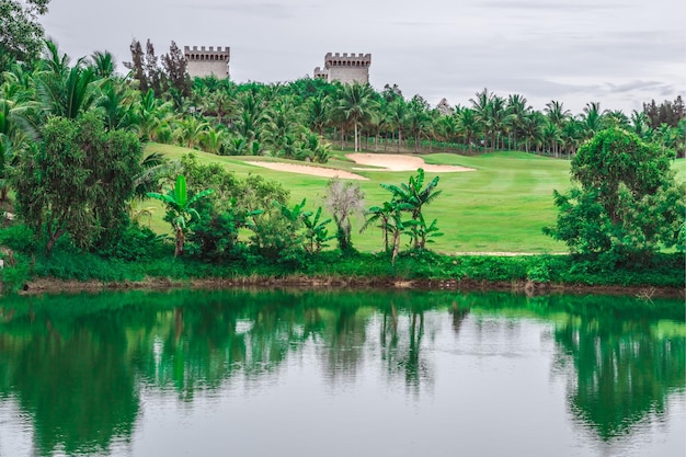 Vista escénica hermoso campo de golf estanque castillo vista de fondo verde césped bosque Reflexión árboles arbusto exuberante en agua paisaje valle lago país parque