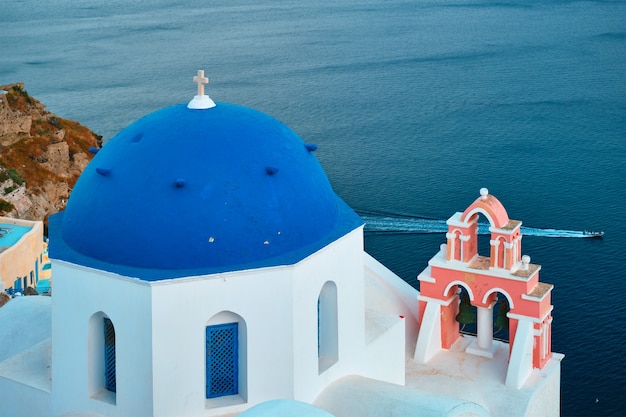 Vista famosa da vila de santorini oia com a cúpula azul da igreja cristã ortodoxa grega