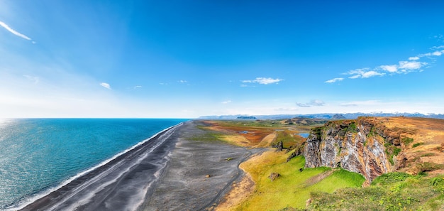 Foto vista fantástica da praia de areia preta de kirkjufjara do promontório de dyrholaey, na costa sul do atlântico