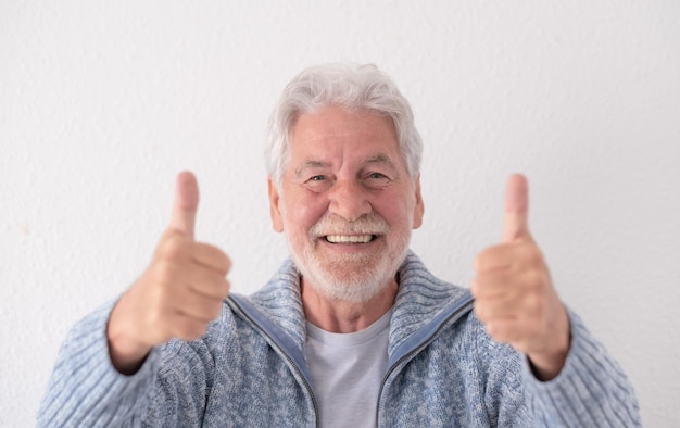 Vista frontal del abuelo senior sonriente feliz mirando a la cámara con los pulgares hacia arriba expresando pensamientos positivos para el futuro