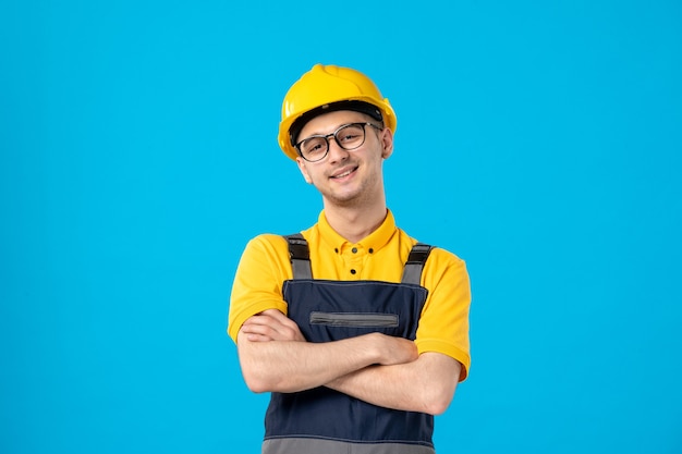 Vista frontal alegre trabajador masculino en uniforme amarillo sobre azul