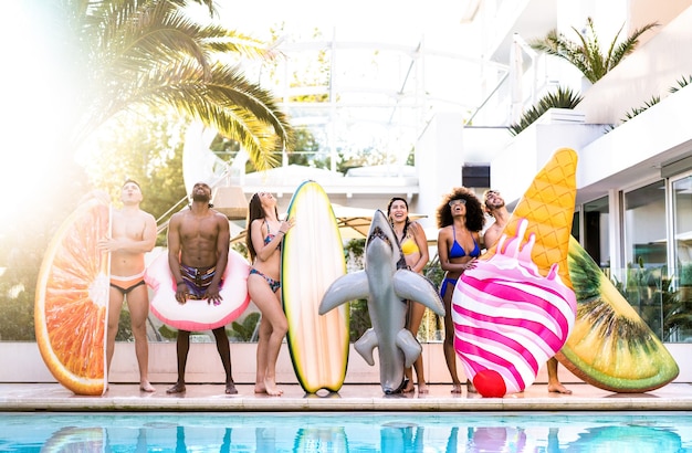 Vista frontal de amigos en la fiesta de la piscina con colchón de aire lilo y ropa de baño