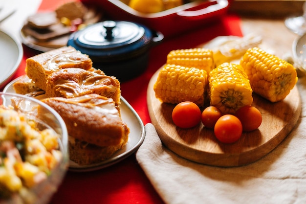 Vista frontal aproximada de um delicioso milho amarelo cozido na mesa de jantar de festa durante o foco seletivo da festa familiar de férias