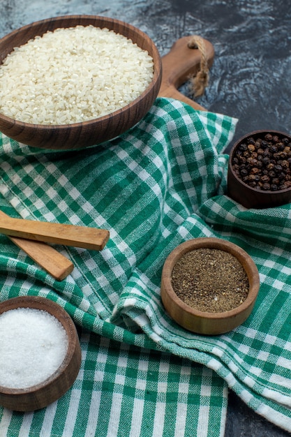 Vista frontal de arroz crudo con condimentos sobre fondo oscuro cereales color comida harina semillas grañones