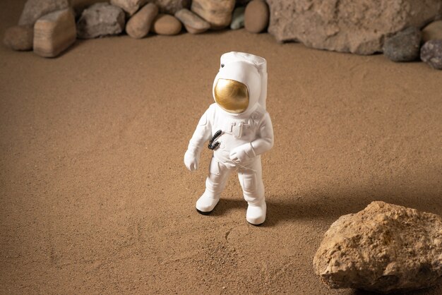 Vista frontal del astronauta blanco alrededor de piedras sobre negro