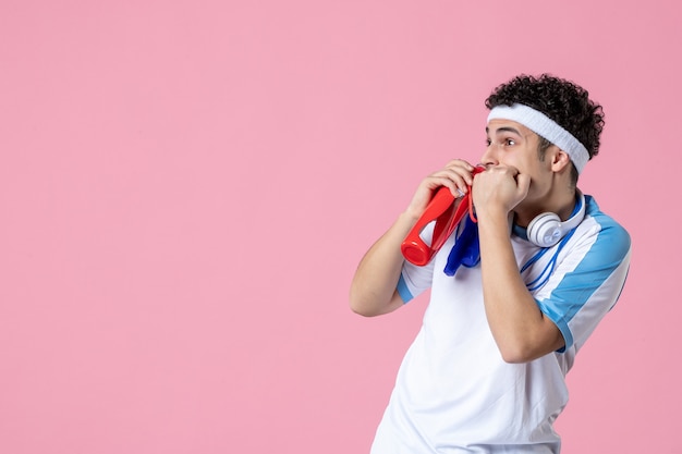 Vista frontal asustado macho joven en ropa deportiva con saltar la cuerda y el agua