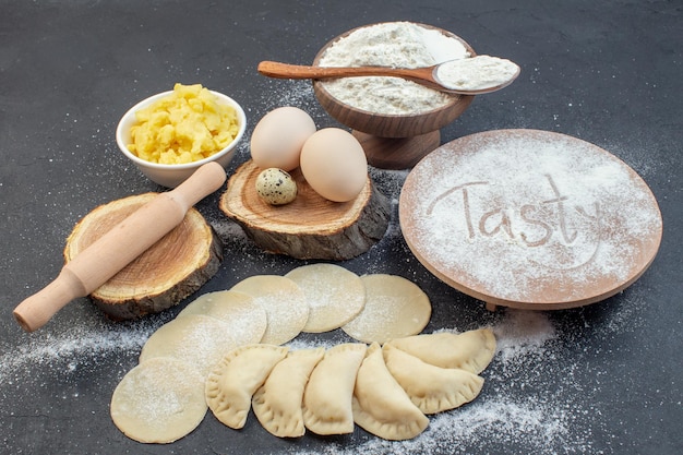 Foto vista frontal, batata crua, pão quente com ovos, batata e farinha no fundo escuro refeição torta biscoito bolo forno assar massa cozinhar