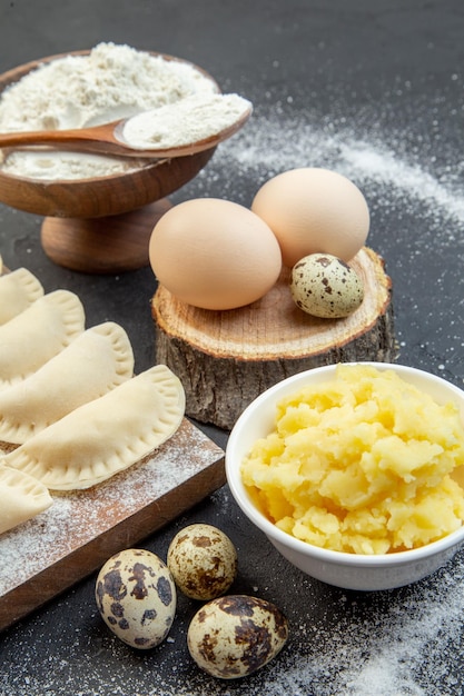 Vista frontal bolinhos quentes crus com farinha de batata e ovos em fundo escuro torta bolo de massa assar pó de cozinha forno de óleo