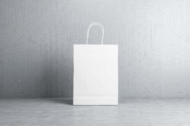 Foto vista frontal en una bolsa de compras de papel blanco en blanco con espacio para su logotipo o texto en el piso de concreto en una maqueta de representación 3d de fondo gris