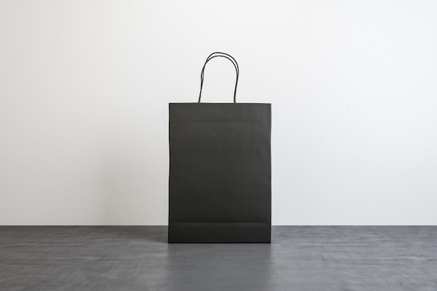Vista frontal en una bolsa de compras de papel negro en blanco con lugar para su logotipo o texto en piso de concreto sobre fondo blanco simulacro de representación 3D