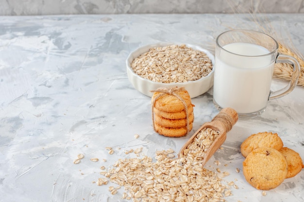 Vista frontal de la botella de leche y galletas de vidrio de leche tazón de avena sobre fondo gris lugar de copia