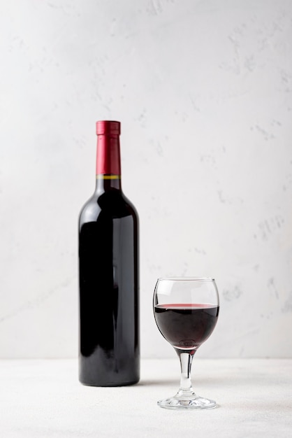 Foto vista frontal botella de vino tinto al lado del vidrio