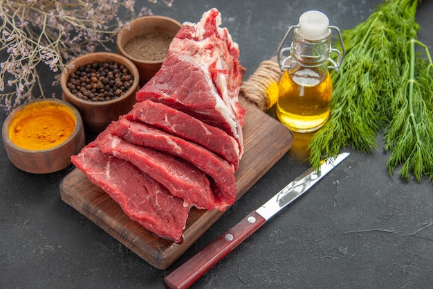 Vista frontal de carne fresca en rodajas con condimentos sobre fondo oscuro comida animal barbacoa color carnicero carne cena comida