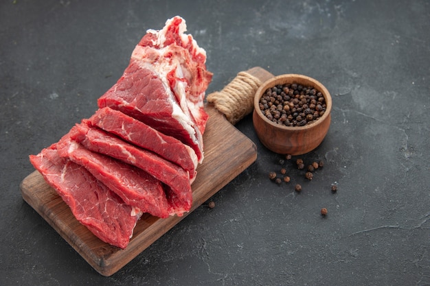 Vista frontal de carne fresca en rodajas con pimienta sobre fondo oscuro carne animal barbacoa cena comida color comida carnicero