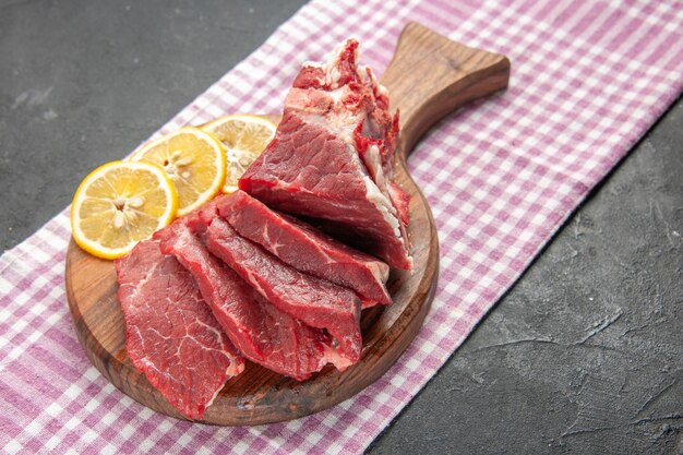 Vista frontal carne fresca en rodajas con rodajas de limón sobre fondo oscuro carne carnicero comida barbacoa comida animal cena cocina