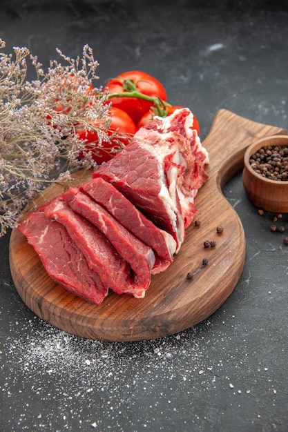 Vista frontal de carne fresca en rodajas con tomates rojos sobre fondo oscuro carne comida cena carnicero animal barbacoa comida color