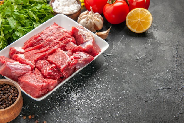 Vista frontal de carne fresca en rodajas con verduras y tomates rojos sobre fondo oscuro comida cena carne barbacoa comida animal carnicero