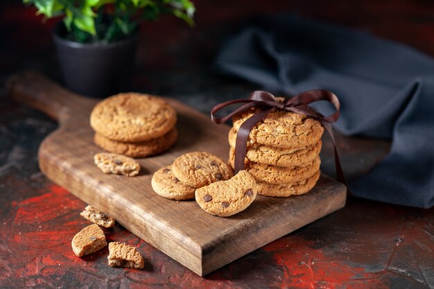 Vista frontal cercana de deliciosas galletas de azúcar caseras sobre tabla de madera y maceta sobre fondo de colores mezcla oscuros