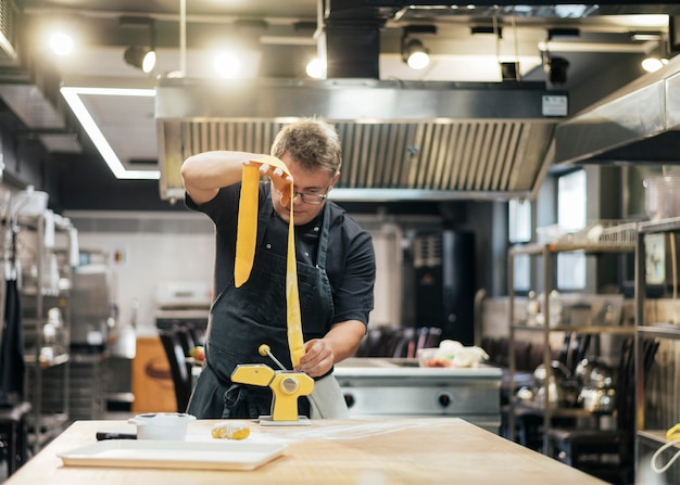 Foto vista frontal del chef masculino rodando masa de pasta