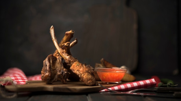 Vista frontal chuletas de cordero sobre tabla de madera con salsa