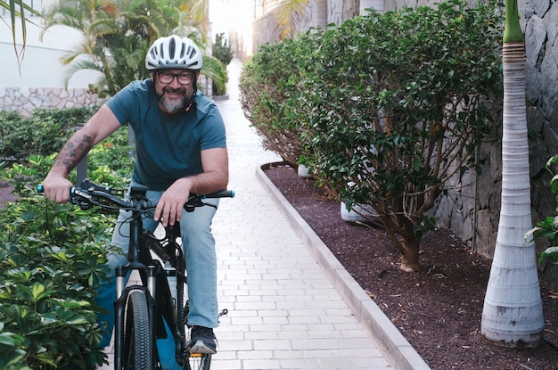 Foto vista frontal de un ciclista sonriente y despreocupado con casco usando una bicicleta eléctrica en una actividad de fin de semana