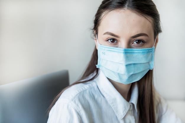 Vista frontal close-up de uma fêmea em óculos profissional de saúde vestindo máscaras cirúrgicas em um hospital. Profissionais de saúde na pandemia de Coronavirus Covid19