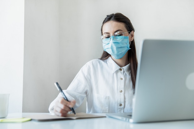 Vista frontal close-up de uma fêmea em óculos profissional de saúde vestindo máscaras cirúrgicas em um hospital. profissionais de saúde na pandemia de coronavirus covid19