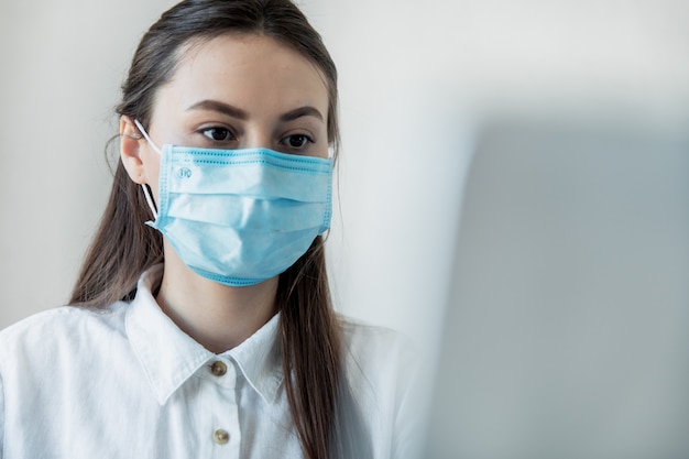 Vista frontal close-up de uma fêmea em óculos profissional de saúde vestindo máscaras cirúrgicas em um hospital. Profissionais de saúde na pandemia de Coronavirus Covid19