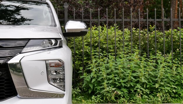 Foto la vista frontal de un coche estacionado frente a una valla metálica cerca de un parque verde