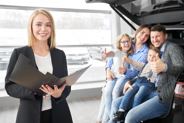 Foto vista frontal del concesionario de automóviles femenino manteniendo el contrato en las manos